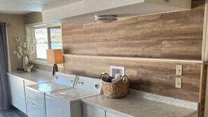 A modern kitchen with a large island, built-in appliances, and a wooden backsplash. - Floating Over The Water! (Chelan)