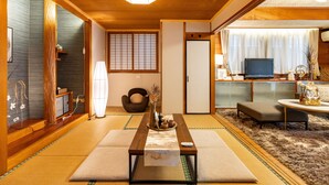 A traditional Japanese room with tatami flooring, a low wooden table, a television, and a sliding door. - Naha House (Naha)