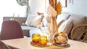 A dining area with a table set for two, featuring a woven pendant light, a vase with dried plants, and a bowl of decorative stones. - Naha House (Naha)