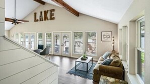 A spacious living area with a high ceiling, a large window, and a ceiling fan. - 5 STAR VIEWS! Boat rental! Chef's kitchen! SUP/kayak/game room/mauimat (Murchison)