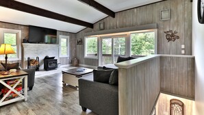 Un salón amplio con chimenea, ventanas grandes y un rincón de estar acogedor.