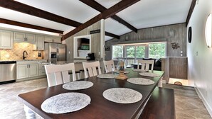 Una cocina moderna con horno empotrado, una mesa de comedor con individuales y vistas al exterior.
