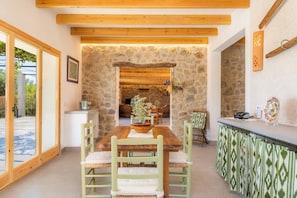 Un espace repas avec une table en bois, des chaises et un mur en pierre en arrière-plan.