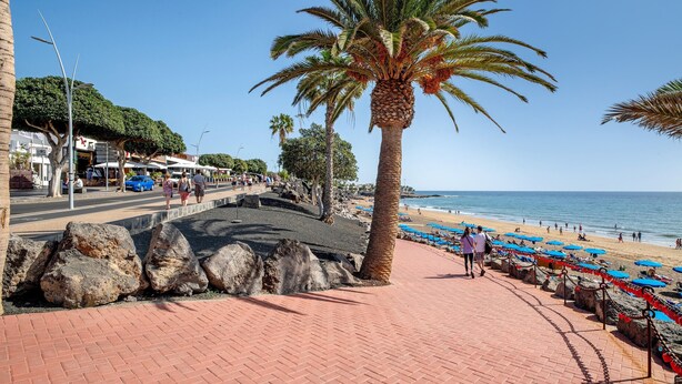 A coastal walkway with palm trees, a beach, and a paved path. - Beachside Villa "Muñoz" with Heated Pool, Air Conditioning & Wi-Fi (Puerto del Carmen)
