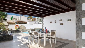 An outdoor dining area with a pool, white walls, and a view of buildings in the background. - Beachside Villa "Muñoz" with Heated Pool, Air Conditioning & Wi-Fi (Puerto del Carmen)