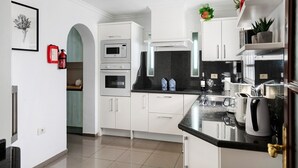 A modern kitchen with white cabinetry, a microwave, oven, and a coffee machine. - Beachside Villa "Muñoz" with Heated Pool, Air Conditioning & Wi-Fi (Puerto del Carmen)
