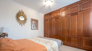 Un dormitorio con cama, un armario grande, un espejo y un cuadro en la pared.