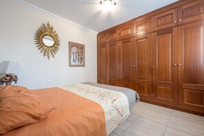 A bedroom with a bed, a large wardrobe, a mirror, and a painting on the wall.