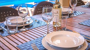 A table set for dining with a bottle of Mounos wine, glasses, and plates. - Vacation Home Villa Karen with Pool & Wi-Fi (Sa Rapita)