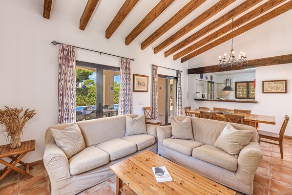A living room with two sofas, a wooden coffee table, and a dining area with a table and chairs.