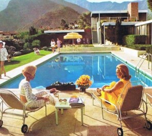 Un espace aménagé au bord de la piscine, comprenant deux chaises longues, une petite table et un arrangement floral.