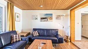 Ein Wohnzimmer mit Holzboden, einem blauen Ledersofa, einem Holztisch und Wandbildern.