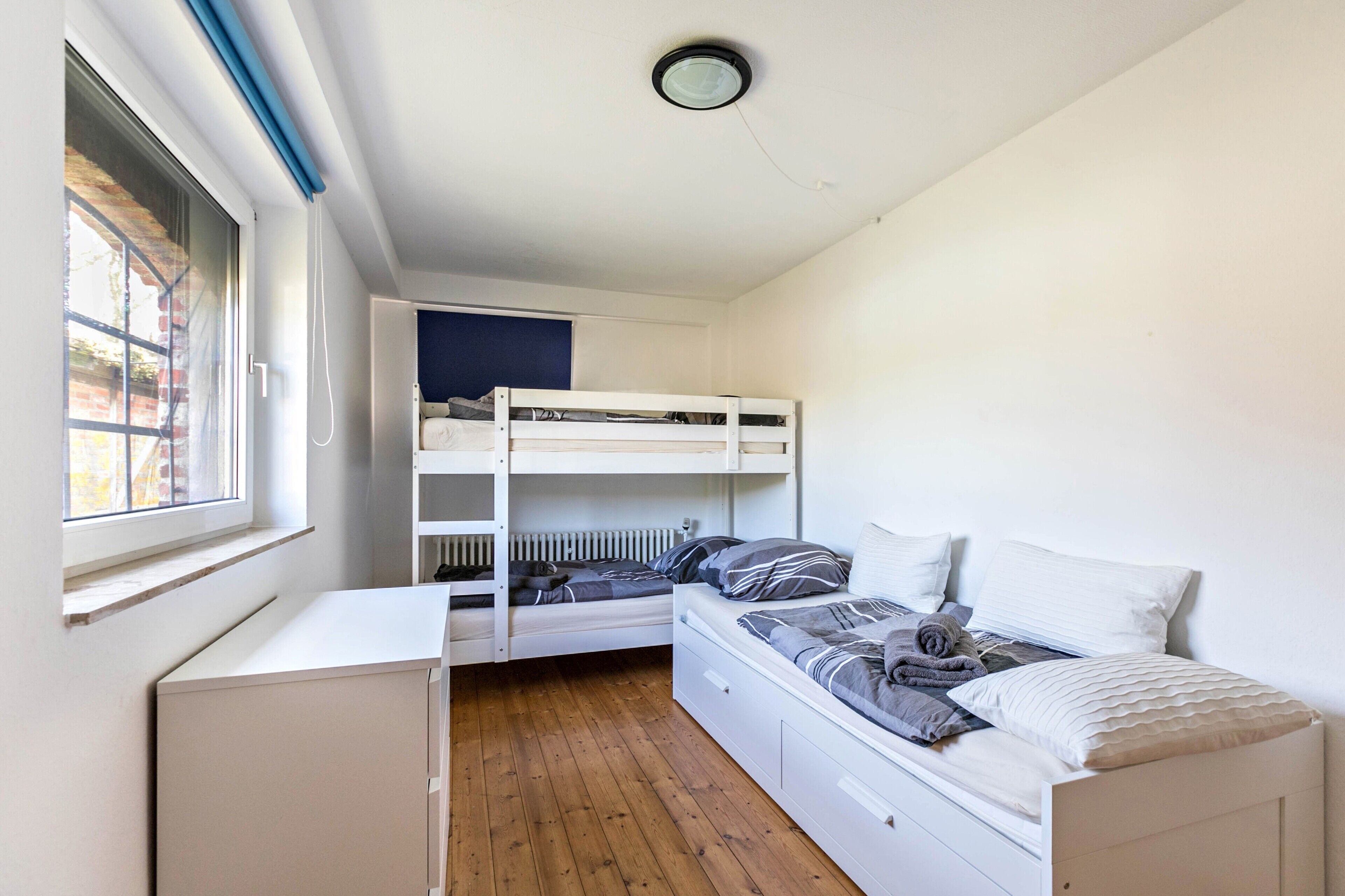 Un dormitorio con literas, un escritorio y una ventana.