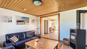 Ein Wohnzimmer mit Holzboden, einem schwarzen Sofa, einem Holztisch und einem Kamin.