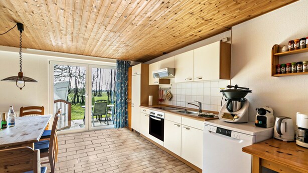 Eine moderne Küche mit Holzboden, weißen Schränken, einem Geschirrspüler und einer Kaffeemaschine.