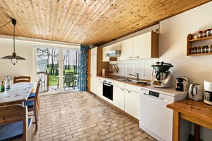 Eine moderne Küche mit Holzboden, weißen Schränken, einem Geschirrspüler und einer Kaffeemaschine.