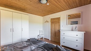Une chambre à coucher comprenant un lit, une armoire, une commode et un miroir.
