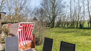 Un espace patio aménagé avec un canapé d’extérieur à rayures rouges et blanches, un meuble en bois et un paravent.