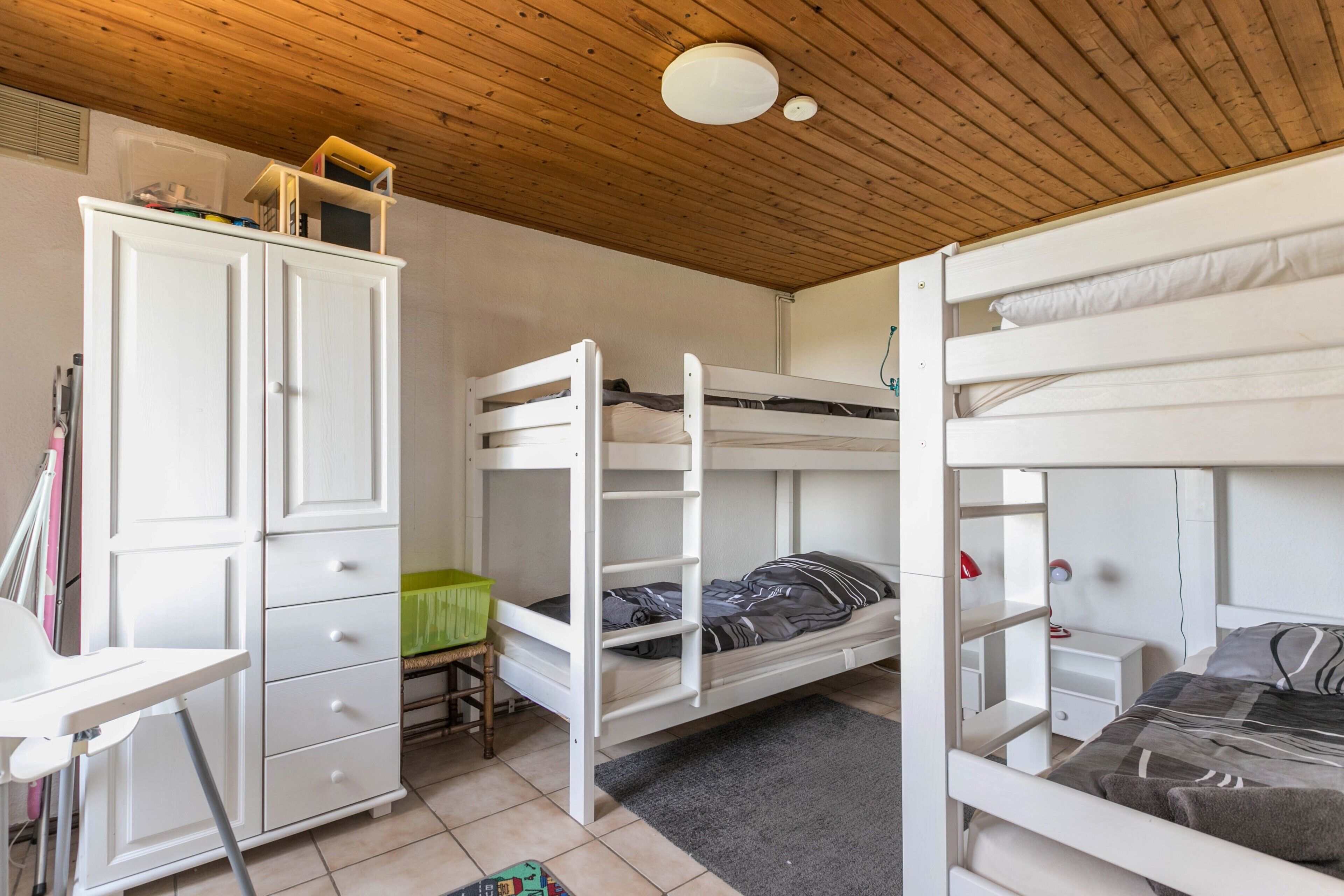 Habitación con literas, un escritorio, un armario y una lámpara en el techo.