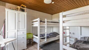 Habitación con literas, un escritorio, un armario y una lámpara en el techo.