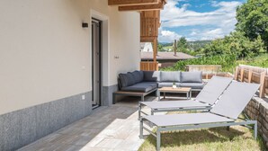 A patio with a sofa, lounge chairs, and a wooden deck. - Holiday Apartment "Roderer" with Mountain View, Wi-Fi, Balconies & Terrace (Völs)