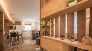 A wooden interior with a dining area, kitchen, and a shelf with plants. - Holiday Apartment "Roderer" with Mountain View, Wi-Fi, Balconies & Terrace (Völs)