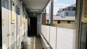A corridor with lockers, a trash bin, and a view of buildings outside. - Gojyo-IVY Semi-double bed 1 (Kyoto)