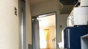 A narrow hallway with wooden flooring, a blue refrigerator, and a desk with a chair. - Gojyo-IVY Twin bed 1 (Kyoto)