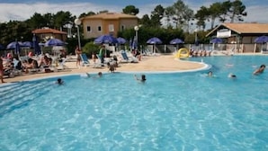 A swimming pool with people swimming and sunbathing.