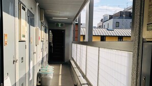 A corridor with lockers, a trash bin, and a view of buildings outside. - Gojyo-IVY Twin bed 2 (Kyoto)
