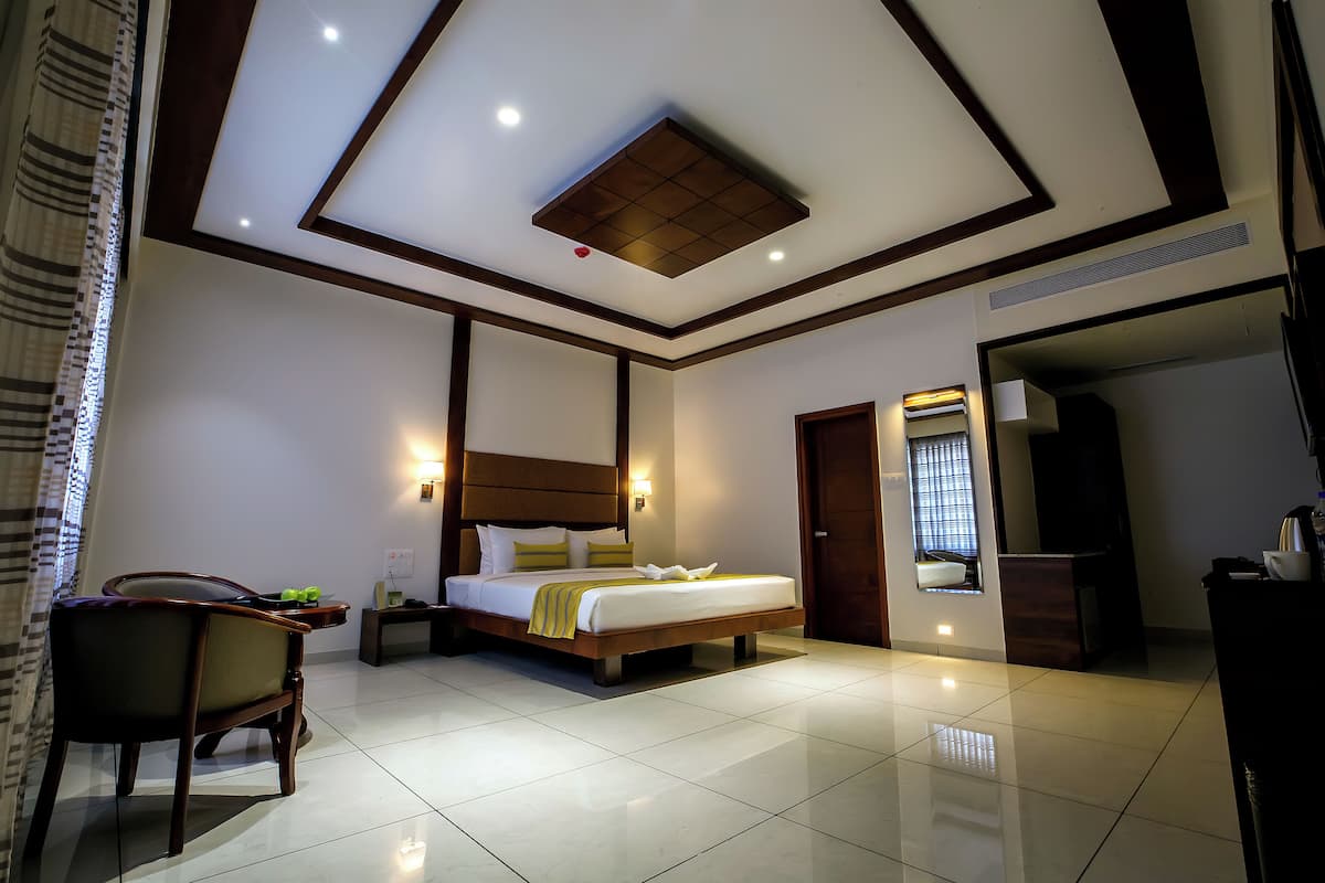 A modern hotel room with a large bed, a bedside table, a chair, and a bathroom visible through an open door.