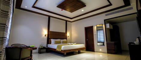 A modern hotel room with a large bed, a bedside table, a chair, and a bathroom visible through an open door.