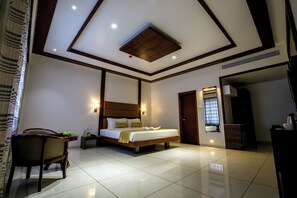 Una habitación de hotel moderna con una cama grande, una mesita de noche, una silla y un baño visible a través de una puerta abierta.