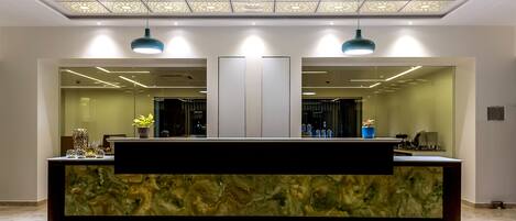 A reception area with a modern design, featuring a marble counter, two pendant lights, and a decorative ceiling.