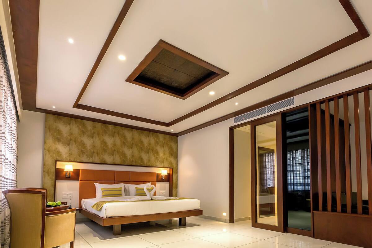 A modern hotel room with a large bed, a ceiling skylight, a sliding glass door, and a wooden floor.