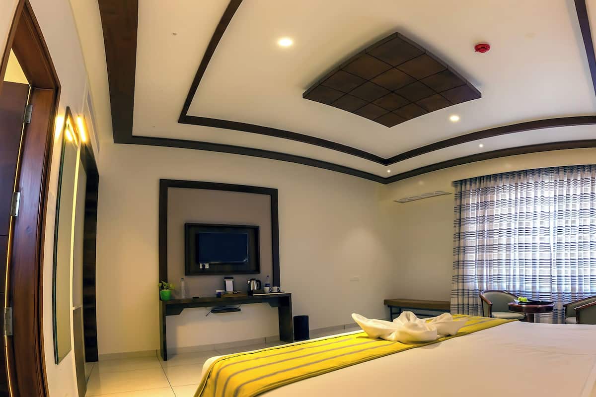 A hotel room with a bed, a desk, a chair, a television, and a window with curtains.