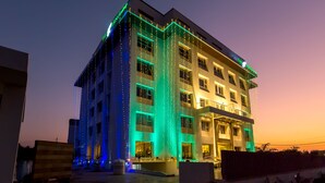 A multi-story hotel with a modern facade, illuminated by vertical string lights. - The Fern Residency, Vijayapura (Bijapur)
