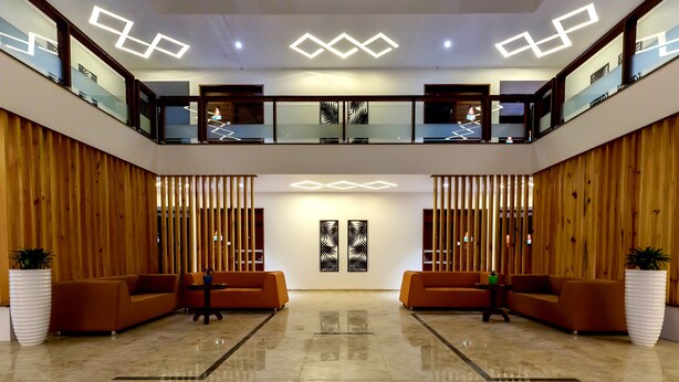 A spacious lobby with a high ceiling, two levels of seating, and modern lighting fixtures. - The Fern Residency, Vijayapura (Bijapur)