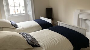 Een slaapkamer met twee bedden, een raam, een stoel en een open haard.