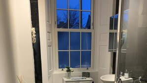 Een moderne badkamer met toilet, bidet en douchecabine met glazen wanden.