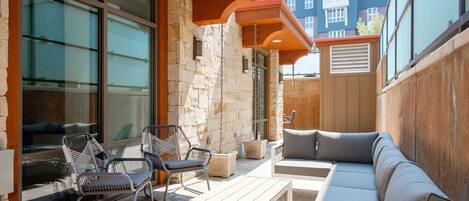 Une terrasse extérieure avec un canapé, des fauteuils et une table.