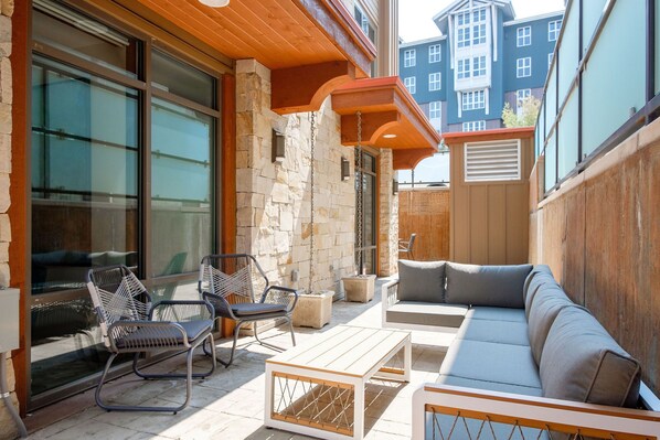 Une terrasse extérieure avec un canapé, des fauteuils et une table.