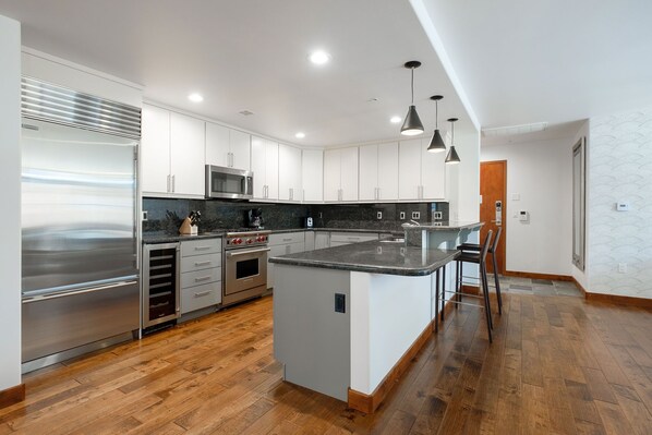 A modern kitchen with stainless steel appliances, white cabinetry, and a wooden floor. - Ski-In/Ski-Out in Park City Mtn. Village - Hot Tub-Managed by Park City Lodging (Park City)
