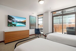 A hotel room with two beds, a wooden dresser, a chair, and a large window with a view.