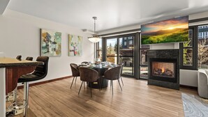 A modern dining area with a round table, chairs, and a fireplace.