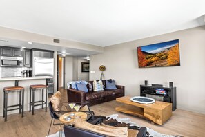 Un salon moderne avec un canapé en cuir, une table basse en bois et un téléviseur à écran plat fixé au mur.
