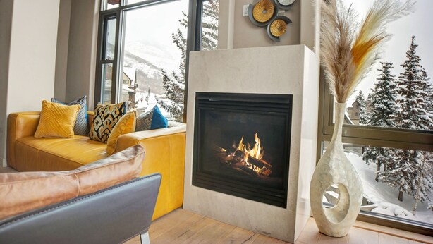 A cozy living room with a fireplace, a yellow sofa, and a large window with a snowy view. - Managed by Park City Lodging-Luxury 2 Bdrm Ski-In/Ski-Out at Park City Mountain (Park City)