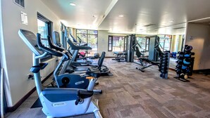 Uma academia com esteiras, aparelhos de musculação e um painel de espelhos.