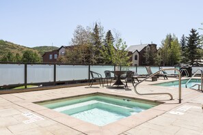 Un espace piscine d’une profondeur de 1 mètre 10, entouré d’une clôture, avec des chaises et des tables, et des maisons en arrière-plan.