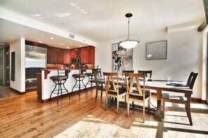 Une cuisine moderne avec des meubles en bois, un îlot central et un coin repas comprenant une table et des chaises en bois.
